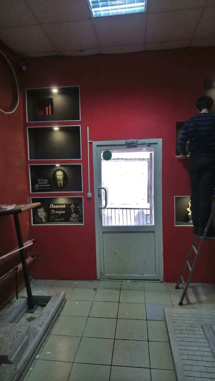 Стена с памятными табличками и образцами оформления мемориалов