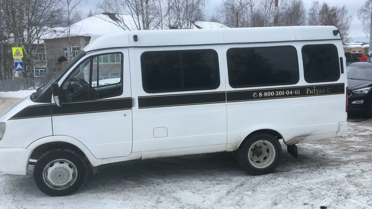 Белый ритуальный катафалк повышенной вместимости на зимней городской улице